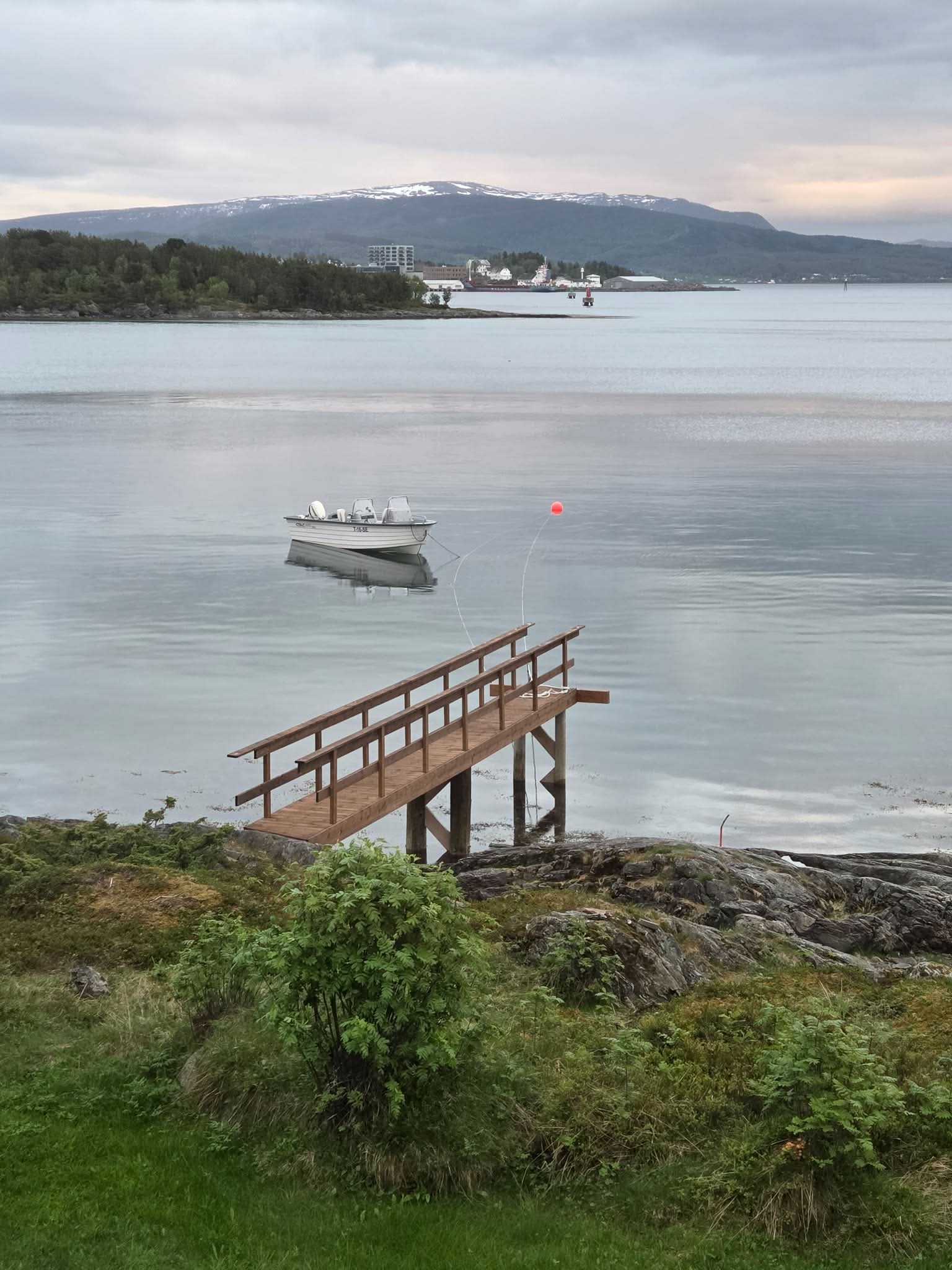 The Eagles & Lines boat moored on a calm inner Senja fjord with snow-capped mountains across the water
